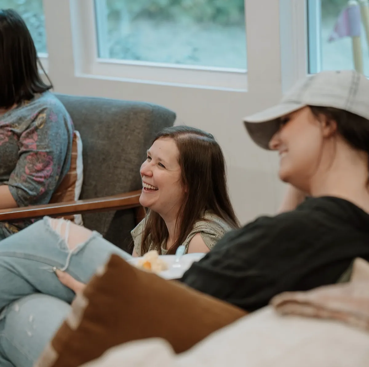 Friends laughing together in a living room at a Nuvo Group in Columbus