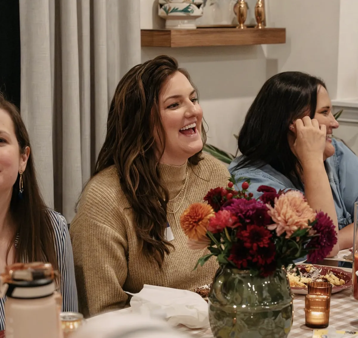 Women laughing around the table at a Nuvo Group dinner party in Dublin, Ohio