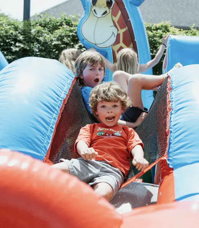 Kids racing down an inflatable slide at a Nuvo Church family event in Columbus