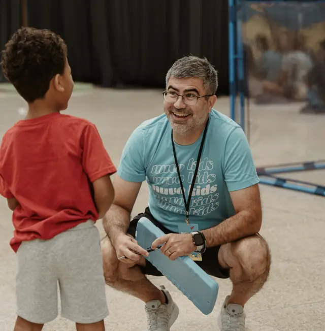 Nuvo Kids volunteer kneeling to talk with an elementary student at church in Dublin, Ohio