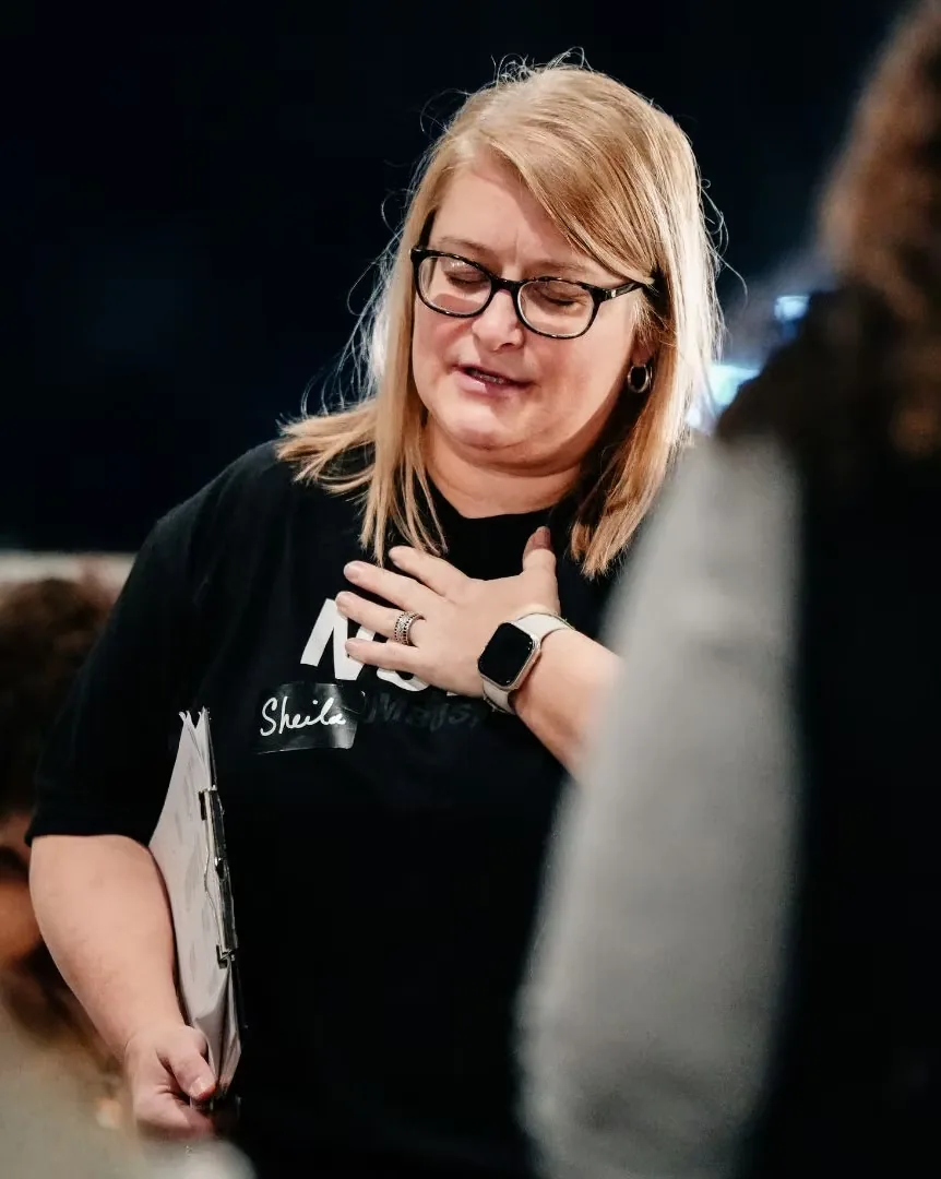 Woman praying with her hand on her heart at Nuvo Church in Columbus