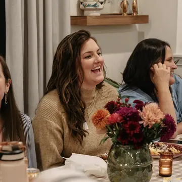Women laughing together at a Nuvo Church dinner party