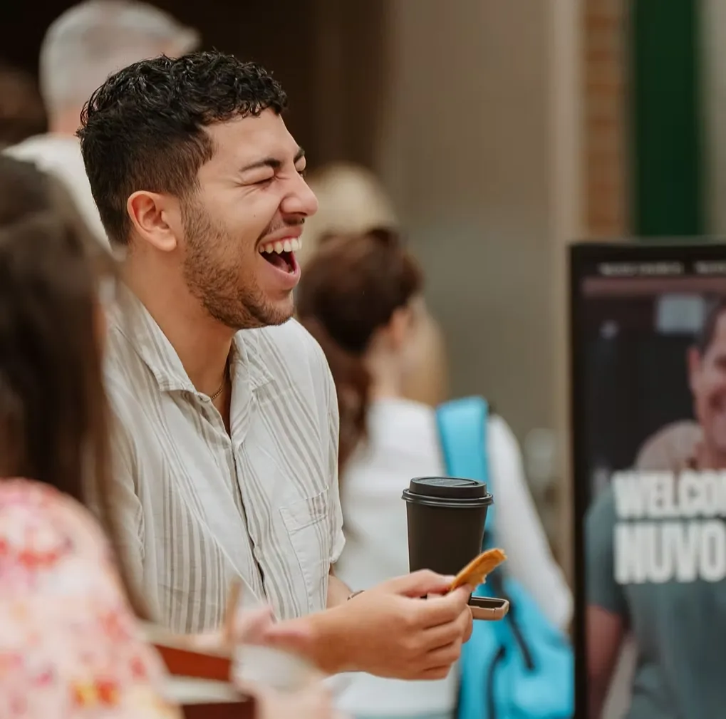 Man laughing with friends over coffee before a Sunday service at Nuvo Church in Columbus, Ohio
