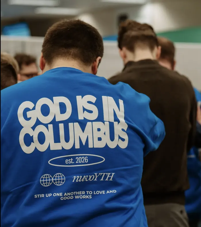 Student wearing a God Is In Columbus Nuvo YTH shirt during prayer at Nuvo Church